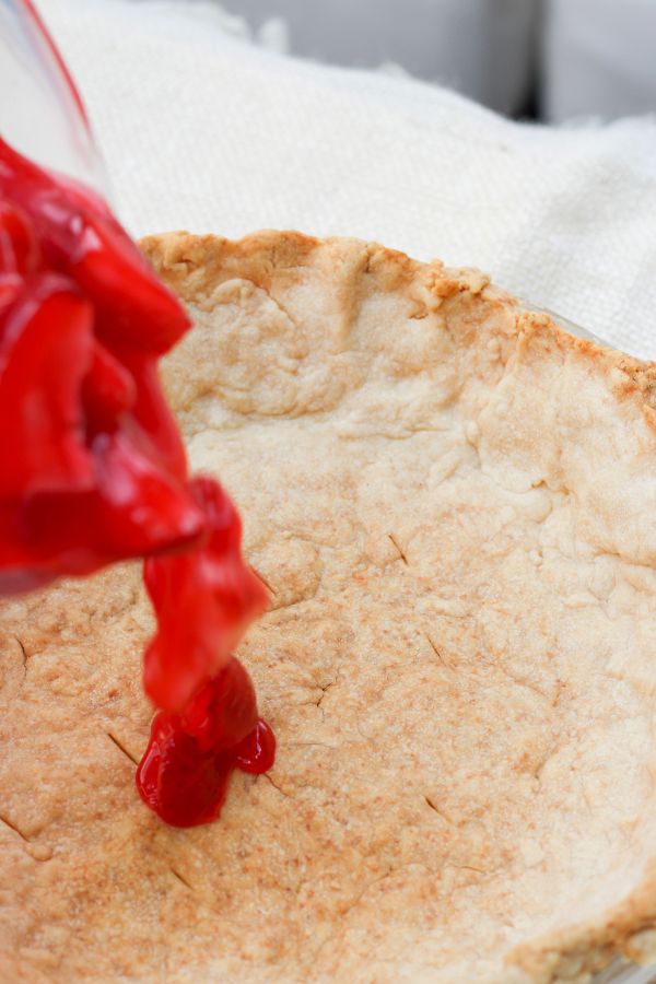 strawberry filling going into a pie shell