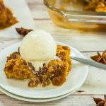 pumpkin pecan cobbler piece on a plate topped with ice ream